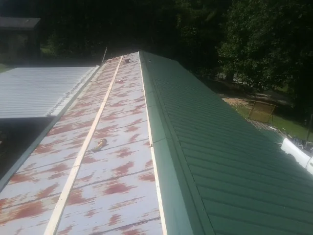 Old rusted panels beside newly installed green metal roofing — Wind Damage Roof Repair by Roofing Brothers in Big Cove Tannery