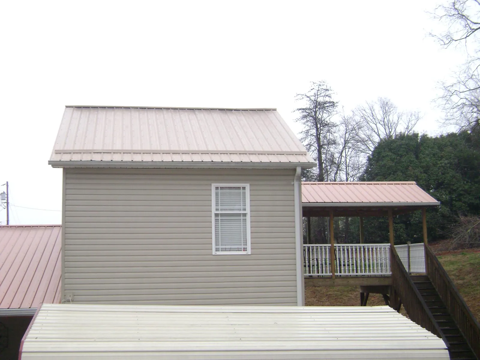 Tan metal roofs on a two story addition and attached porch, from a Roof Replacement job in Big Cove Tannery