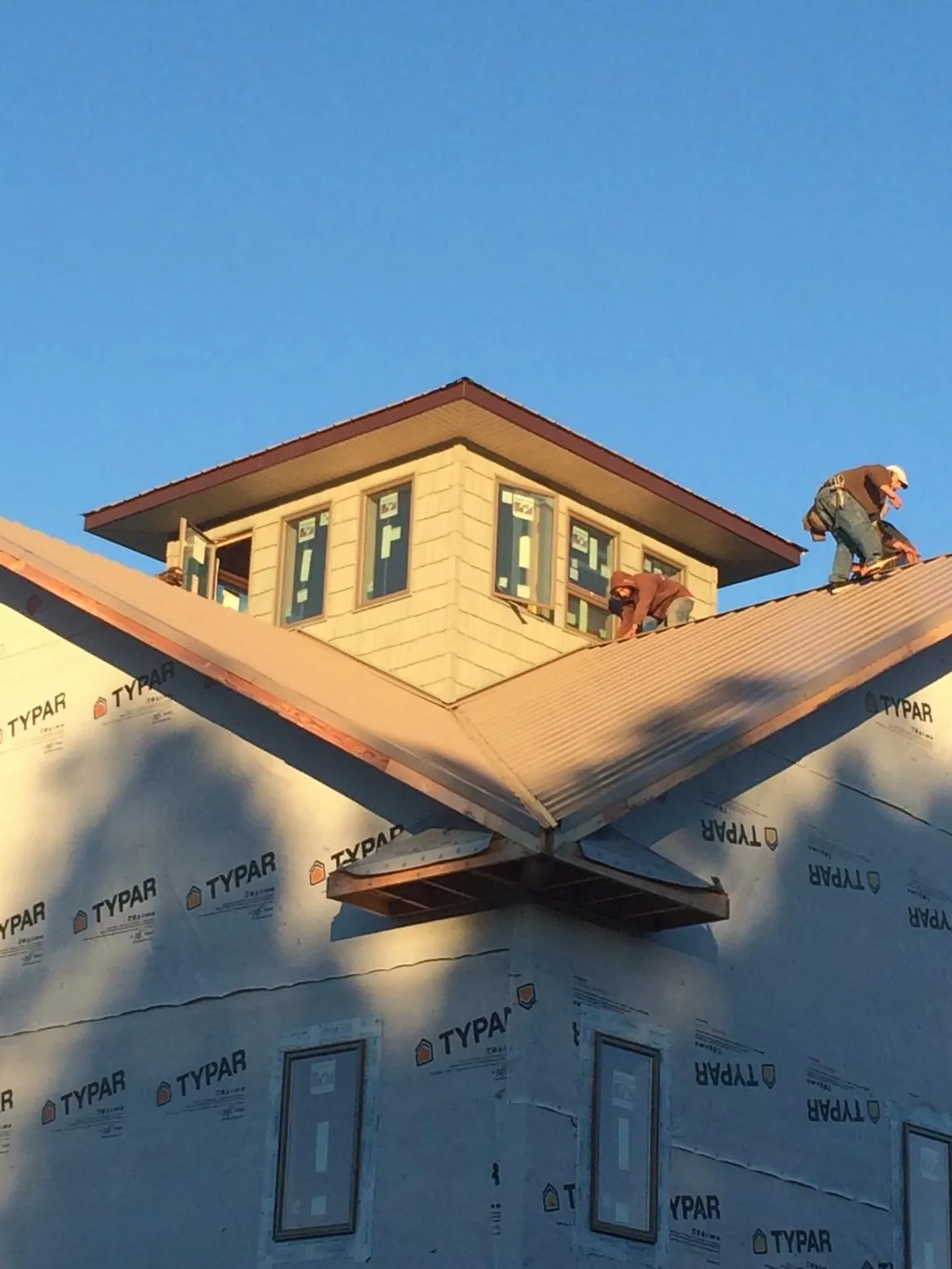 Roofers working around a rooftop cupola on a new metal roof at sunset — Roof Waterproofing in Big Cove Tannery by Roofing Brothers